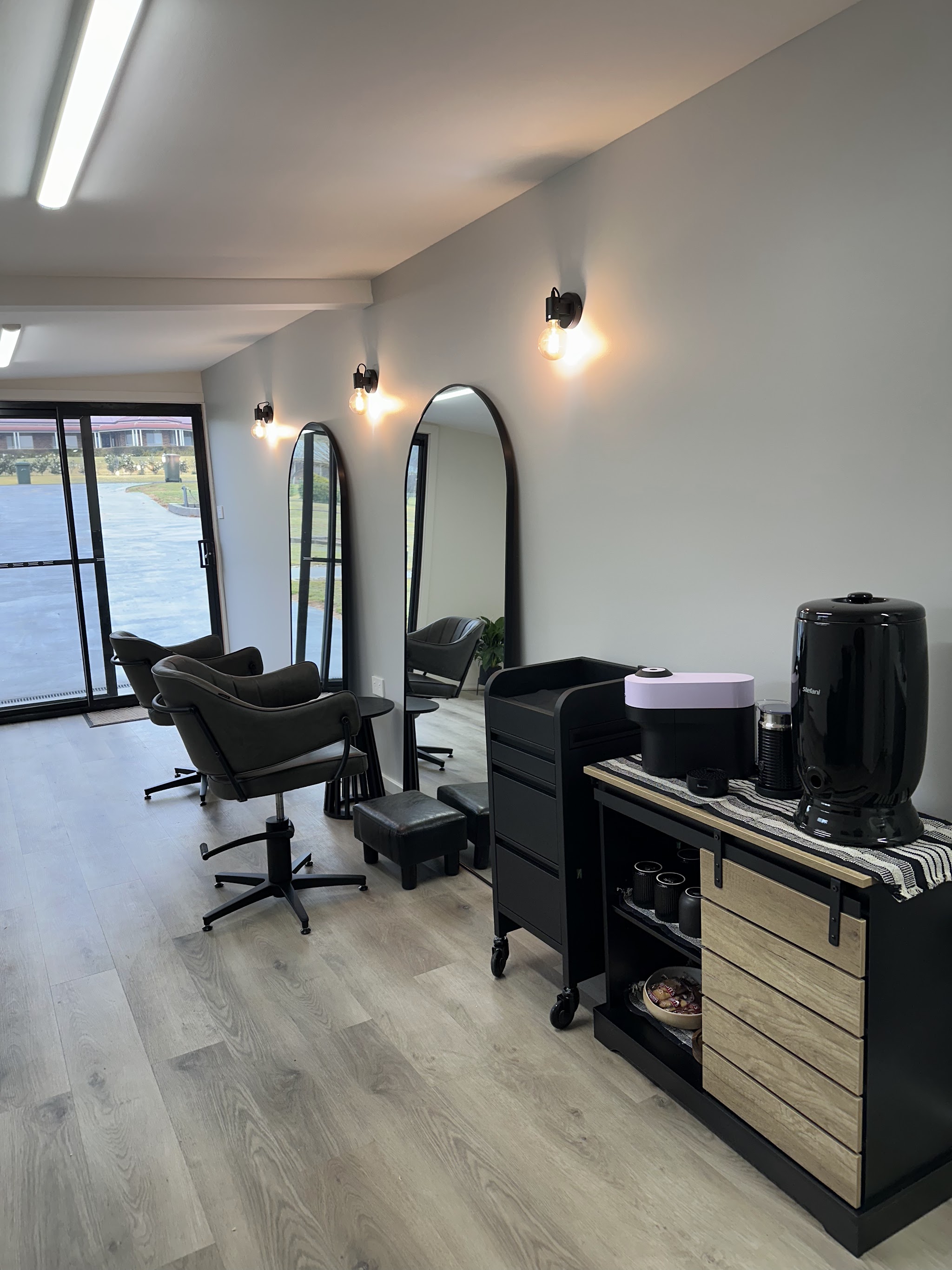 Styling chairs in front of tall arched mirrors, with warm wall lights